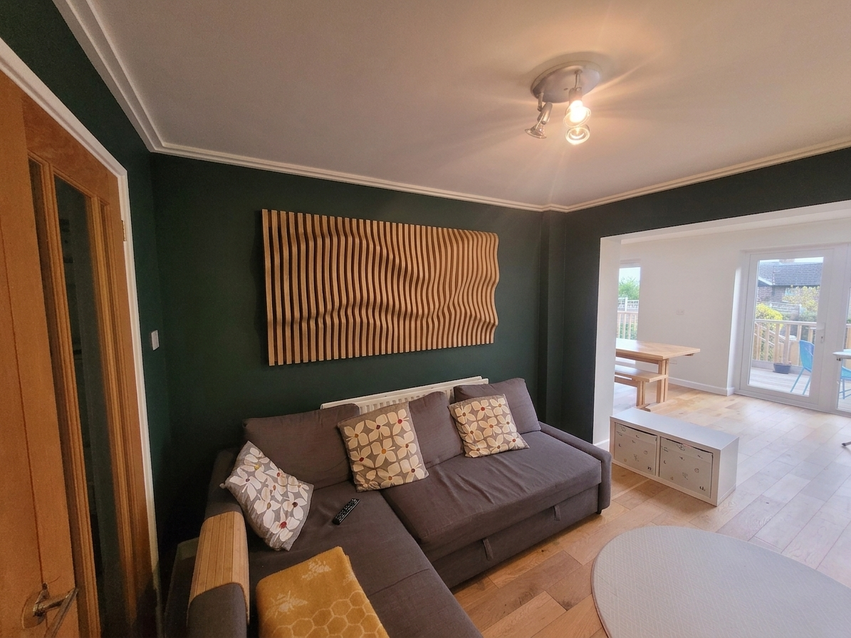 Oak wave panel above a grey sofa in a sunlit living room